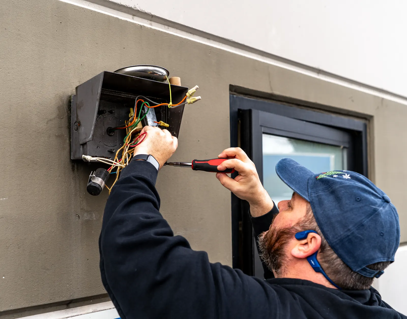 Electrical Support technician troubleshooting an exterior wiring junction during an inspection and repair call.
