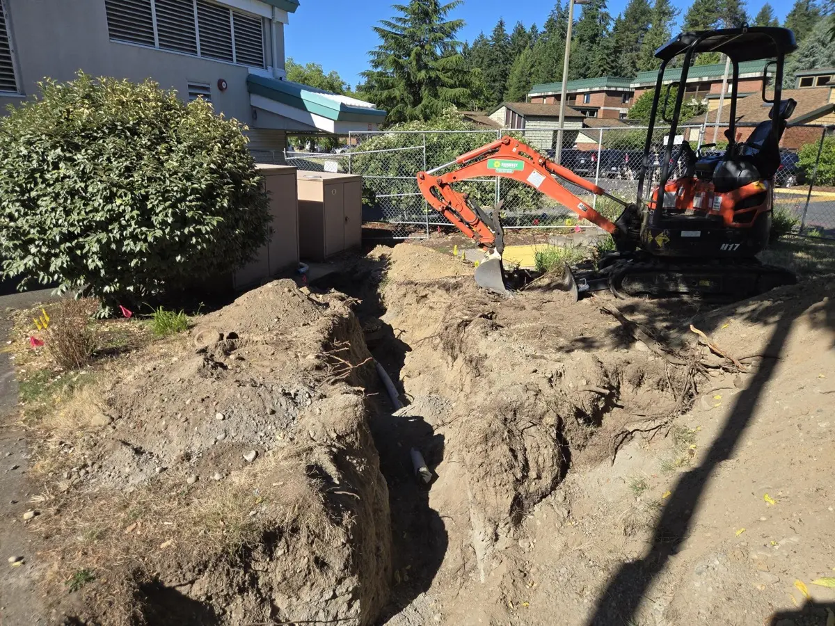 Conduit fittings staged in an open trench during rough-in