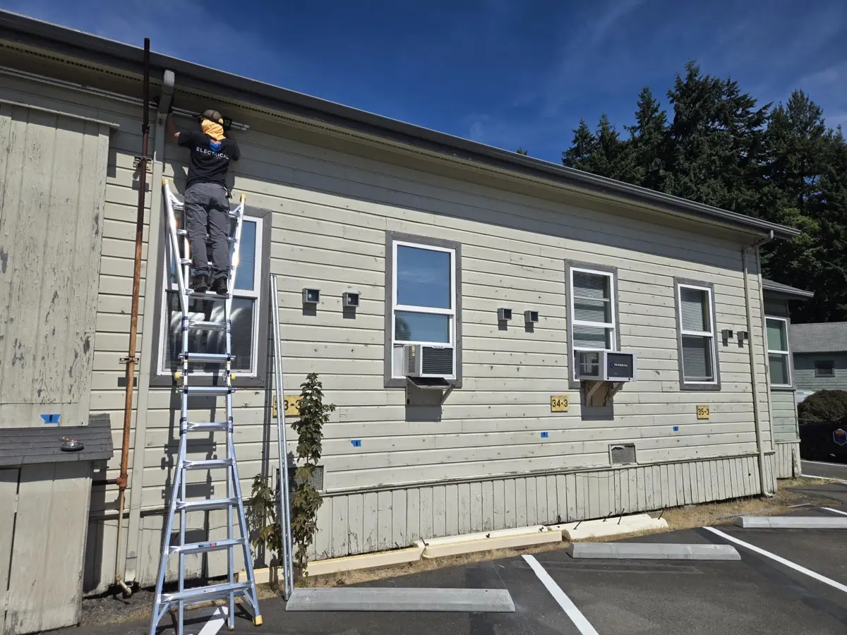 Electrician installing conduit along the roofline of the fleet building
