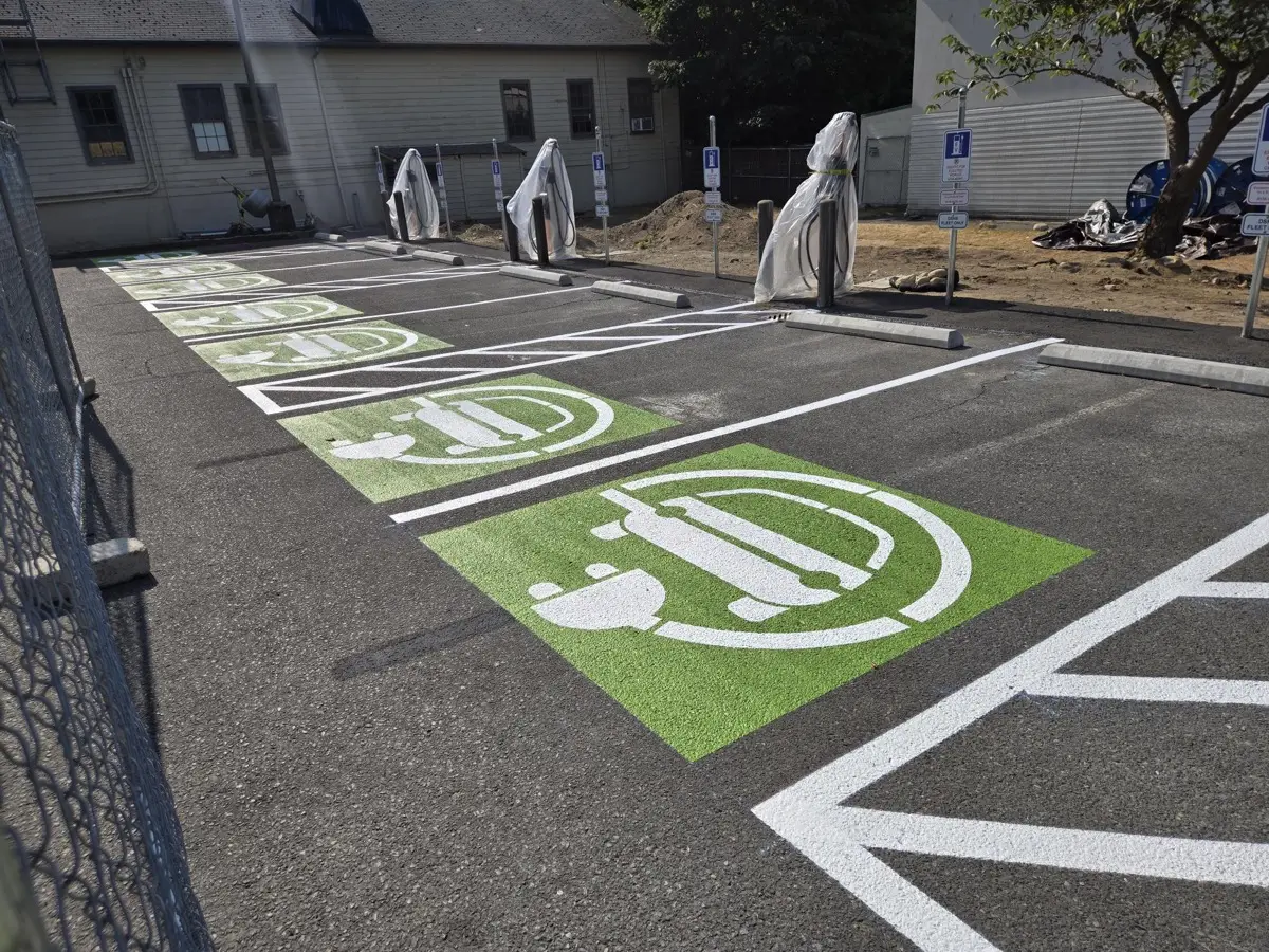 Marked EV charging stalls with painted charging symbol at a DSHS fleet lot